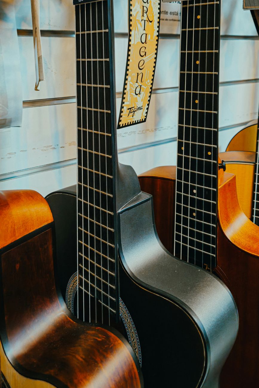 Multiple classical guitars on display in a music store, showcasing different wood finishes and intricate details.